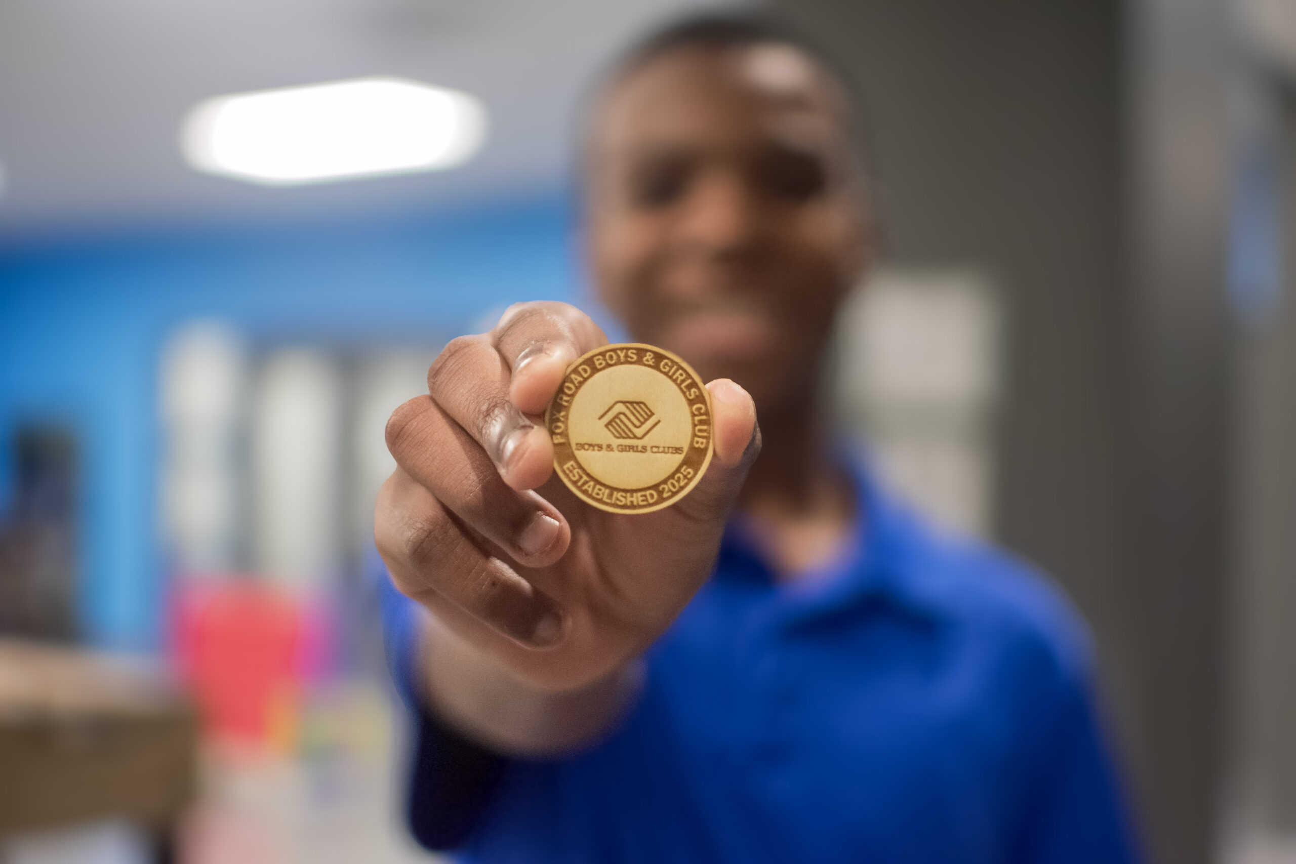 Person holding a Fox Road Boys & Girls Club coin